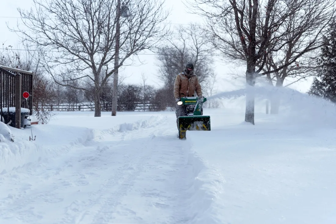 An operator clearing a long private driveway during heavy snowfall
